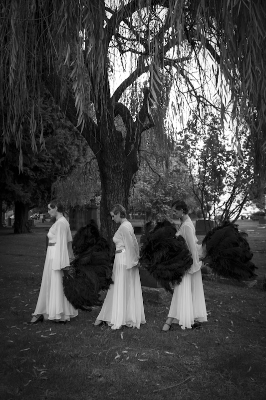 three dancers wearing white costumes walking in cemetery